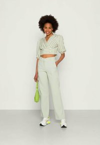 Blusa curta de vichy verde com mangas bufantes, combinada com calças verdes claras de cintura alta. Complementada com uma bolsa verde e ténis brancos.