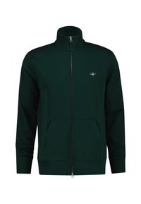 Dunkelgrüne Zip-Jacke mit hohem Kragen, Fronttaschen und gerippten Bündchen. Besitzt ein kleines Logo auf der Brust. Weicher Stoff.
