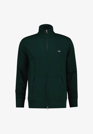 Dunkelgrüne Zip-Jacke mit hohem Kragen, Fronttaschen und gerippten Bündchen. Besitzt ein kleines Logo auf der Brust. Weicher Stoff.
