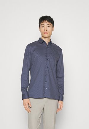 Marineblaue Button-Up-Bluse mit einem kleinen weißen Pünktchenmuster, langen Ärmeln und einem spitzen Kragen. Baumwollstoff mit einer glatten Textur.