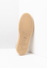 Suela de sneaker color crema con goma texturizada, que presenta un diseño minimalista y un detalle de la bandera italiana. Talla 42, construcción robusta.