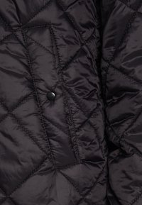 Schwarze gesteppten Jacke mit einem Rautenmuster, glatter Textur und einem Druckknopfverschluss auf der Brusttasche.