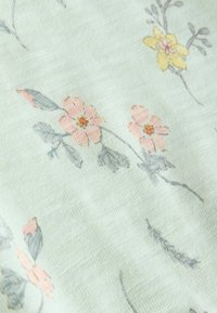 Floral-patterned fabric in light mint green. Features delicate pink and yellow flowers with gray leaves, soft texture, and subtle weave.