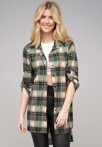 Camicia a quadri verde e beige con maniche arrotolate, realizzata in tessuto morbido. Presenta un taglio dritto e un design con colletto classico.