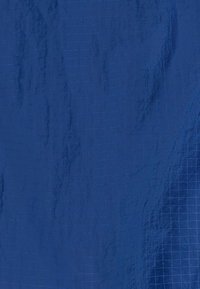 Tissu bleu profond avec une texture lisse, présentant un motif en grille subtil et une légère brillance sur toute la surface.