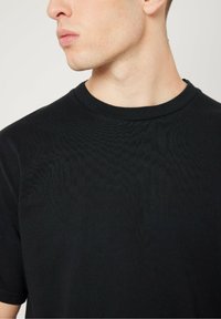 Black short-sleeve t-shirt with a round neckline. Smooth texture and a fitted design, highlighting the upper torso area.