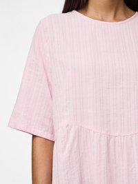 Gaiši rozā kleita ar vertikālām svītrām, īsām piedurknēm, apaļu kakla izgriezumu un plūstošu augšu ar salocītiem elementiem.