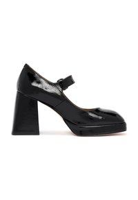 Chaussure Mary Jane en cuir verni noir avec un bout rond, un devant plat et un talon épais. Équipée d'une seule sangle ajustable.