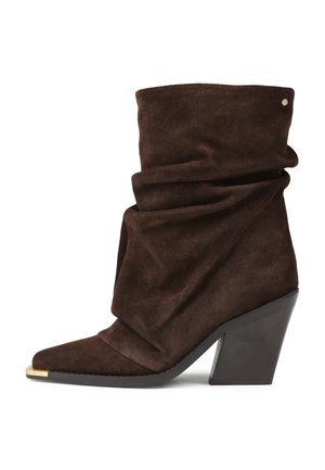 Bottines en daim marron avec un design plié, bout pointu et un accent argenté au bout. Présente un talon épais pour plus de stabilité.
