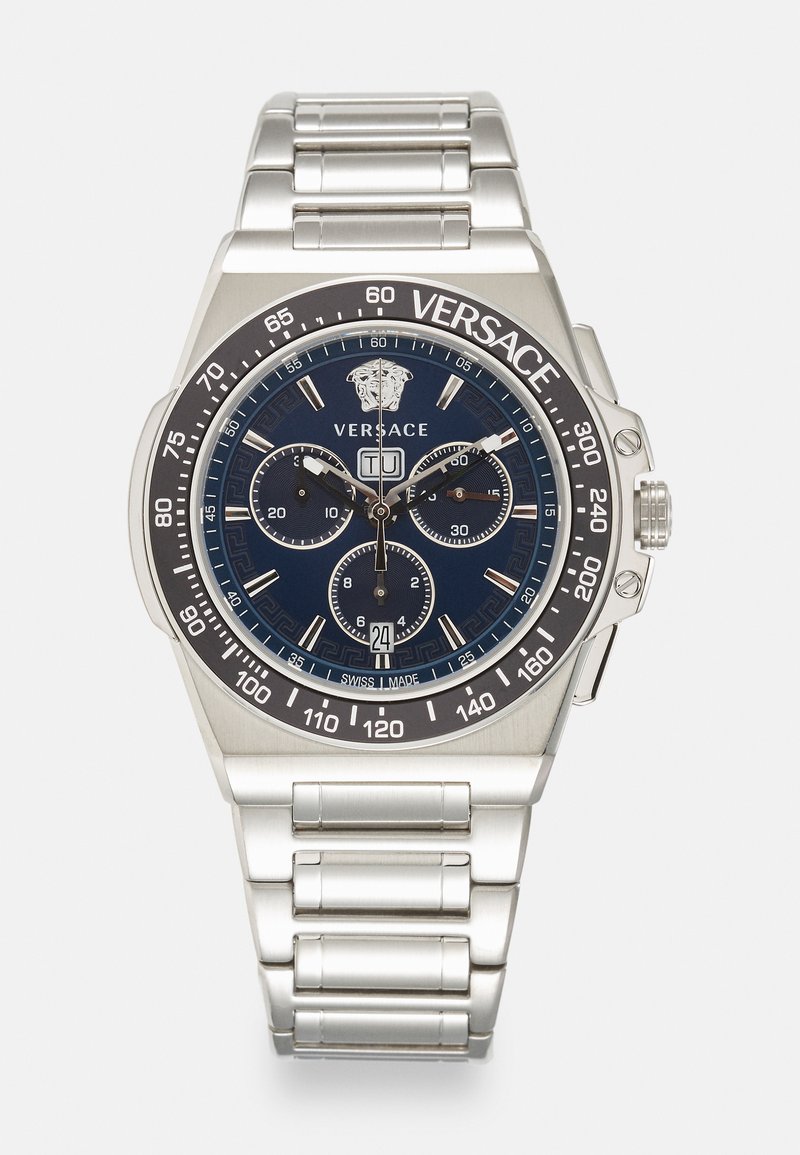 Silver stainless steel chronograph watch with a blue dial, three sub-dials, and a Versace logo. Features a marked bezel and patterned accents.