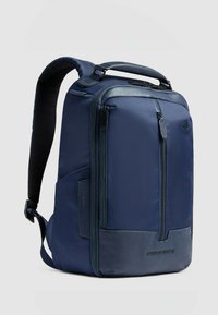 Zaino blu navy con una texture resistente, caratterizzato da un mix di nylon e dettagli in pelle, multiple tasche con cerniera e spallacci imbottiti.