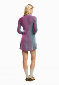 Neulemekko pitkillä hihoilla, jossa on liukuvärjätty kuvio vaaleanpunaisena ja sinisenä, vartalonmyötäinen malli ja liehuva helma. Yhdistetty polvisukkien ja kenkien kanssa.