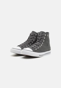 Visoke tenisice od sive tkanine, s bijelim gumiranim vrhom i potplatom, zatvaranjem na vezanje i metalnim rupicama. Teksturirana površina.