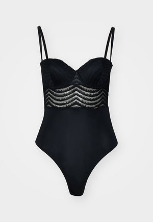 Juoda bodysuit su nėriniuotu uždengimu, turinčiu zigzago raštą, su palaikymo puodeliais ir plonomis reguliuojamomis petnešomis. Lygi medžiaga su aukštai iškirptomis kojomis.