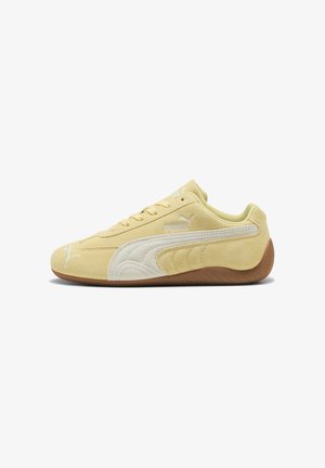 Niski żółty zamszowy sneaker Puma z białym paskiem z boku i brązową gumową podeszwą, pokazany z lewej strony.