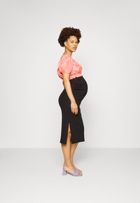Top cor-de-rosa com mangas bufantes em combinação com uma saia midi preta justa com uma fenda lateral; complementado por sandálias de salto lavanda.