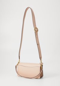 Light pink leather crossbody bag with a curved design, detachable strap, and gold hardware accents. Smooth texture with minimal stitching.