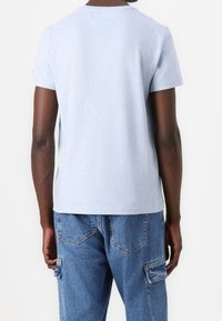 Světle modré tričko s krátkým rukávem a kulatým výstřihem, vyrobené z jemné tkaniny, s volným střihem, v kombinaci s modrými cargo kalhotami.