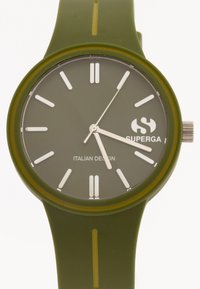 Zelen silikonast ure s krožno skrinjo, belimi oznakami ur in kovinsko krono. Ima "Superga" logotip in napis "Italijanska zasnova".