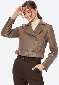 Braune Lederjacke in cropped Form mit Kragen, Frontreißverschluss, mehreren Taschen und einem taillierten Gürtel. Glatte Textur mit dezentem Glanz.