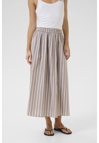 Raikka beige maxi-hame, jossa on valkoisia pystyraitoja, joustava vyötärö ja kevyttä kangasta. Yhdistetty valkoiseen toppiin ja mustiin sandaaleihin.