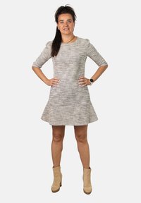 Vestido gris texturizado con mangas tres cuartos y dobladillo acampanado, combinado con botas de tobillo beige. Diseño simple sin patrones visibles.