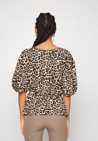 Blus med leopardmönster med puffärmar, insvängd midja och rundad halsringning, med en synlig bakre stängning. Texturerat tyg.