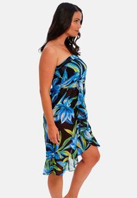 Funda negra transparente con un patrón floral tropical en azul y verde, con dobladillo rizado y diseño sin tirantes. Tejido ligero ideal para la playa.