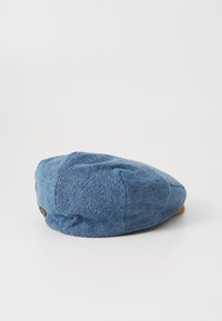Boné de denim azul com um formato arredondado e design de painéis. Tecido texturizado com um pequeno detalhe de couro com marca na parte de trás.