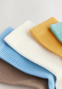 Five folded ribbed knit socks in brown, light blue, white, mustard yellow, and teal arranged overlapping on a white surface.