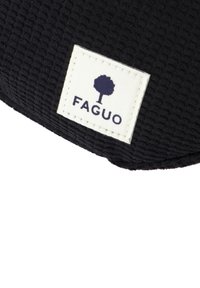 Tela negra texturizada con un parche de logo que presenta un árbol y el texto "FAGUO" en azul marino. La tela tiene un patrón tejido.