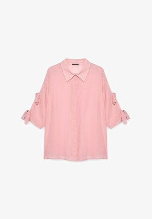 Camicia rosa chiaro con colletto e maniche corte, dotata di lacci sui polsini e chiusura frontale con bottoni. Realizzata in un tessuto morbido e leggero.