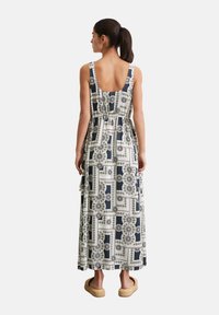 Maxi jurk met een marineblauw en witte geometrische print, ronde rug, gerimpelde taille en zijzakken. Gemaakt van lichtgewicht stof.