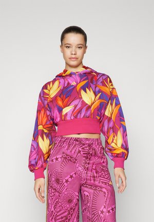 Bluza crop z kapturem w kwiatowy wzór w jasnych kolorach; połączona z różowymi spodniami w geometryczne wzory z elastycznym pasem.