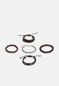 Ensemble de cinq bracelets comprenant du cuir brun, des perles en bois et une chaîne en argent ; textures et formes variées, avec des fermetures ajustables.