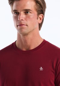 Bordeaux T-shirt met korte mouwen van katoen, met een ronde hals en een klein wit geborduurd pinguïnlogo op de linkerkant van de borst.