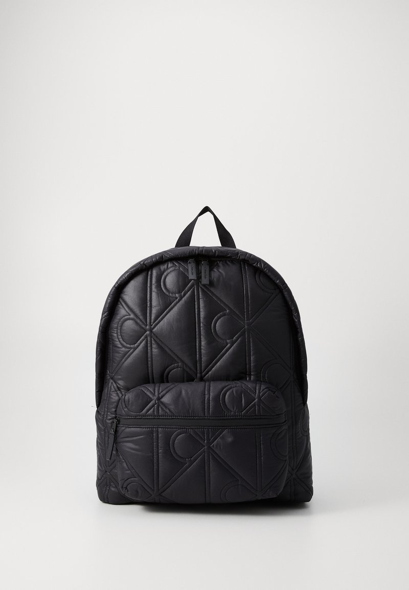 Zaino nero trapuntato con design imbottito, loghi in rilievo, tasca frontale con zip e spallacci regolabili.