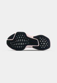 Schuhsohle aus strukturiertem schwarzem Gummi mit einem Muster aus Rillen und Löchern, ergänzt durch einen zartrosa Akzent entlang der Kante.