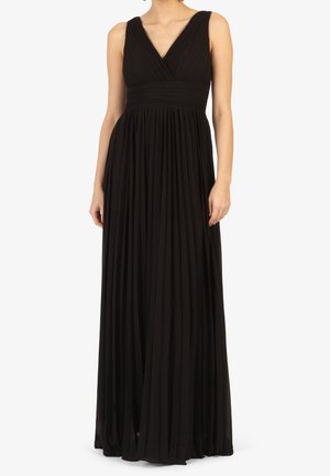 Bez rękawów czarna plisowana sukienka maxi z dekoltem w serek i dopasowaną talią, noszona przez stojącą osobę na jednolitym tle.