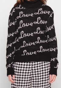 Černý pletený svetr s opakujícím se motivem "Love" v bílé barvě, s vysokým límcem, žebrovanými manžetami a spodním lemem, texturovaná tkanina.