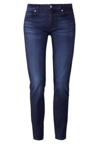 Jeans de denim azul oscuro con un corte ajustado, diseño de cinco bolsillos y cierre de botón de metal. La tela presenta una textura suave y un desgaste sutil.