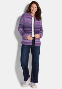 Lila gestreifter Cardigan mit rundem Ausschnitt, Knopfverschluss und strukturiertem Stoff, kombiniert mit dunklen Jeans und hellen Sneakers.