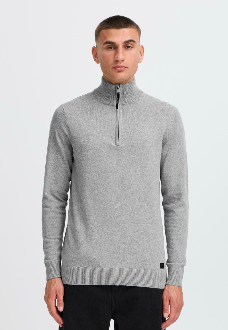 Grå stickad tröja med hög krage och halmvärmare, ribbade muddar och nederkant samt en minimalistisk design.