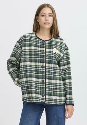 Veste à carreaux verte et crème avec des accents noirs, dotée d'un col arrondi, d'une fermeture à boutons et d'un petit motif brodé sur la poitrine.