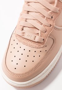 Ljust rosa lädersneaker med perforerat tåparti, texturerade mockadetaljer, platta snören och gummisula. Har en "AF1"-tag.