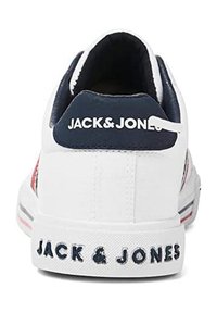 Baskets blanches avec un accent bleu marine au talon. Présente des rayures rouges et bleu marine ainsi qu'une semelle texturée blanche avec la marque "JACK & JONES".