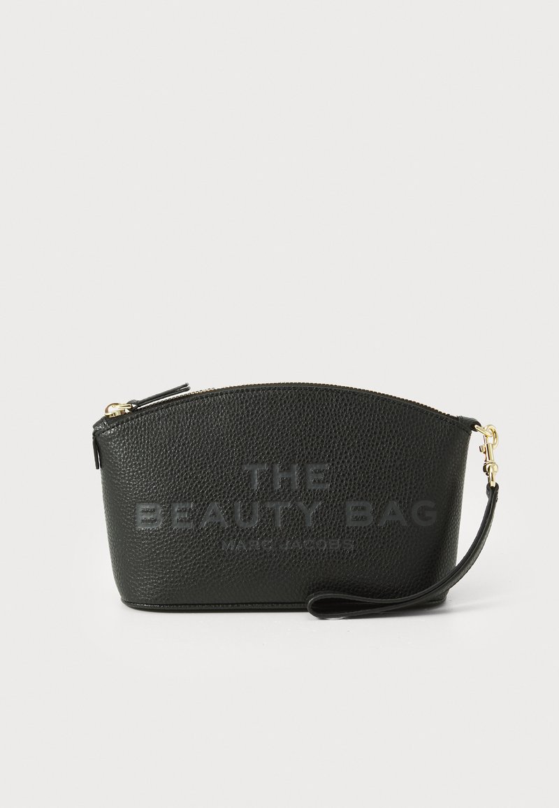 Čierna kozmetická taška s textúrovanou kožou a zaobleným tvarom, s embosovaným textom "THE BEAUTY BAG" a "MARC JACOBS", so zipsom a zápästným popruhom.
