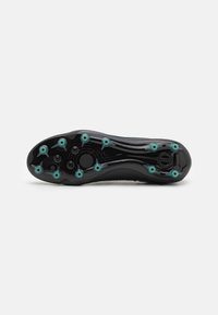 Suela de bota de fútbol negra con tacos en color teal, que presenta un diseño curvado y una superficie texturizada para mejorar la tracción. Incluye una prominente media suela circular.