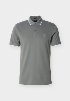 Olívazöld, pamut poloing két gombos gombolású, fehér részlettel a gallérnál és az ujjszegélyeken, négyzet alakú logóval a mellkason.