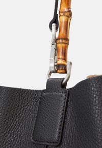 Borsa a tracolla nera in pelle con finitura texturizzata, dotata di manico in bambù e accessori metallici per un attacco sicuro.